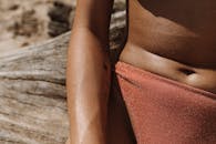 一名身穿闪闪发光泳衣的女子在海滩享受阳光明媚的一天的详细特写