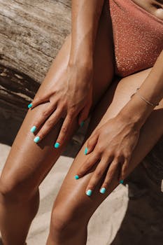 Close-up of woman's hands on sunlit sandy beach, showcasing vibrant summer vibe.