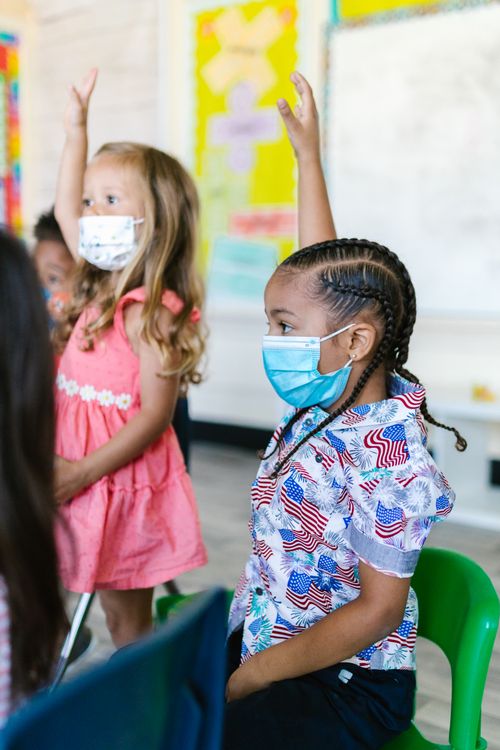Free Young children in a classroom wearing face masks, participating actively. Stock Photo