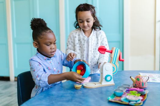 Two young girls playing and learning with toys in a classroom setting.