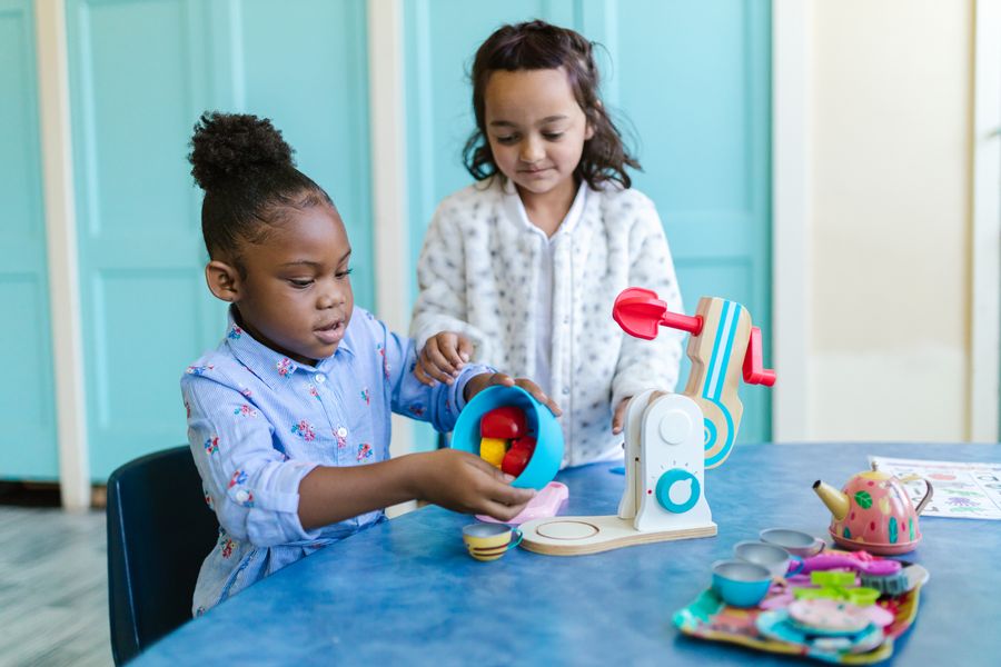 Two children playing together with a wooden tea set