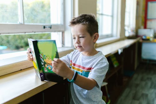 Boy in Gray Crew Neck T-shirt Holding a Book