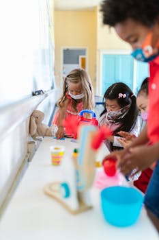 Kids engaged in creative play at school with masks on, promoting safe learning.