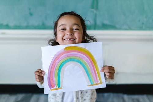 Free Little Girl Holding White Paper with Rainbow Drawing Stock Photo