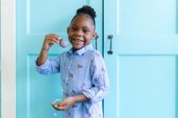Girl in White and Blue Floral Button Up Shirt Standing Near White Wooden Door