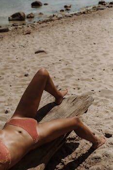 A woman sunbathes on a beach in swimwear, highlighting a peaceful summer vibe.