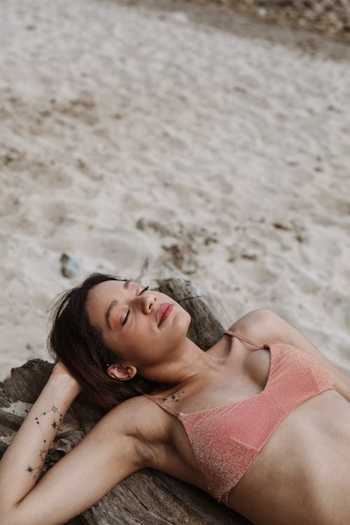 Woman in Pink Bikini Top Lying on Tree Log