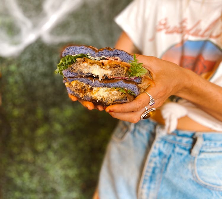 Woman Holding A Burger In Her Hands