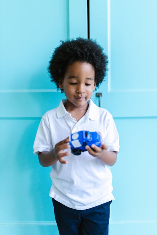 A Boy Playing with Blue Toy Car