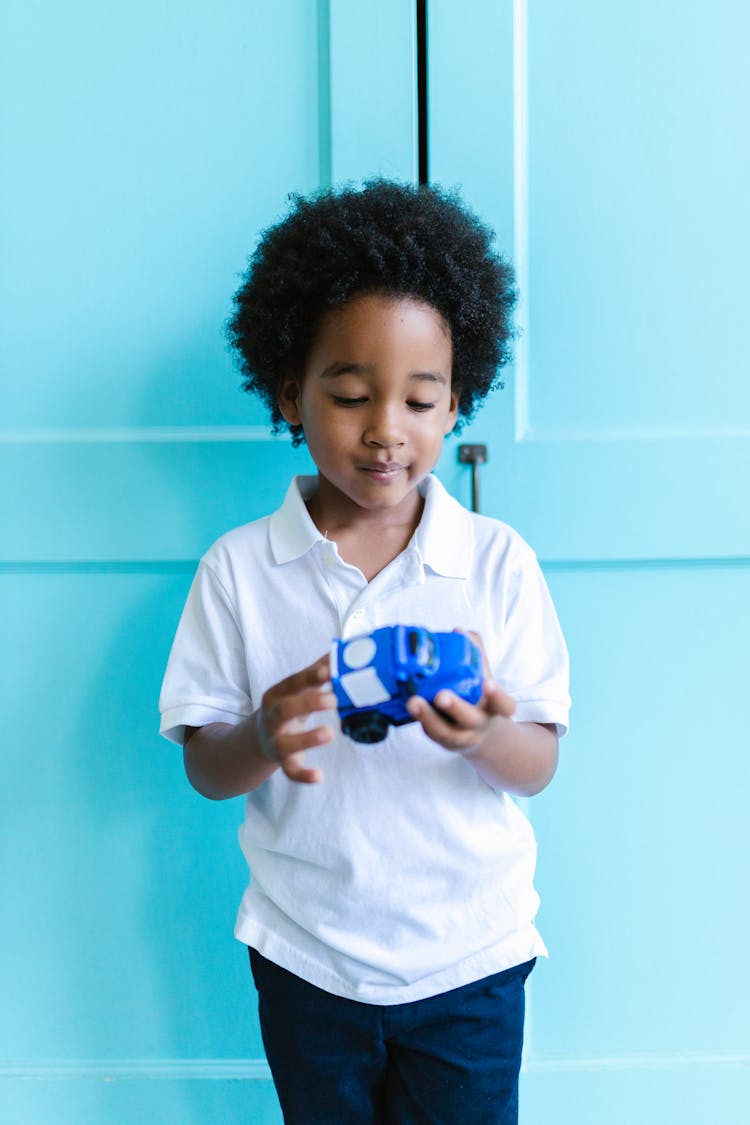 A Boy Playing With Blue Toy Car