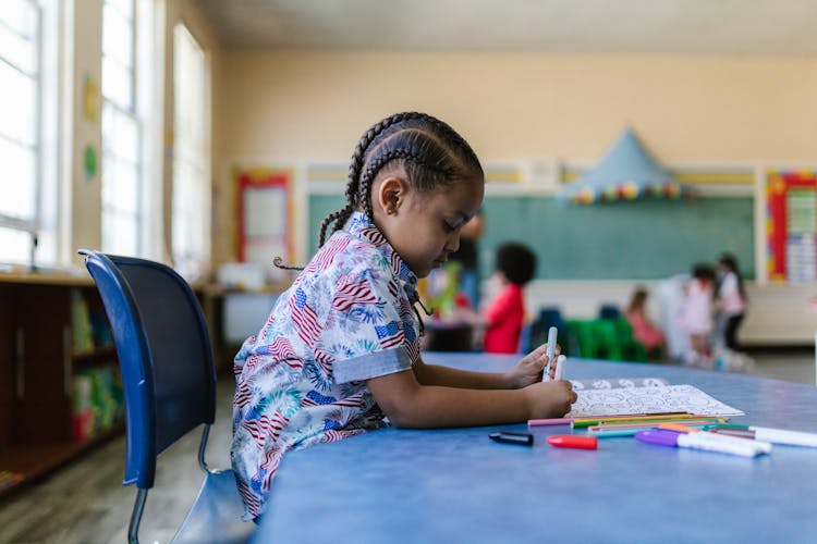 A Girl Sitting On A Blue Chair In The Classroom