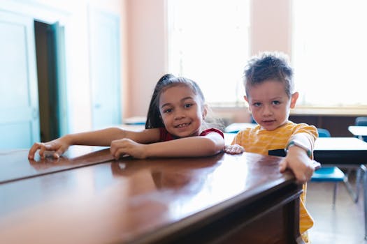 Cheerful children posing at a table in a bright classroom enjoying school time.
