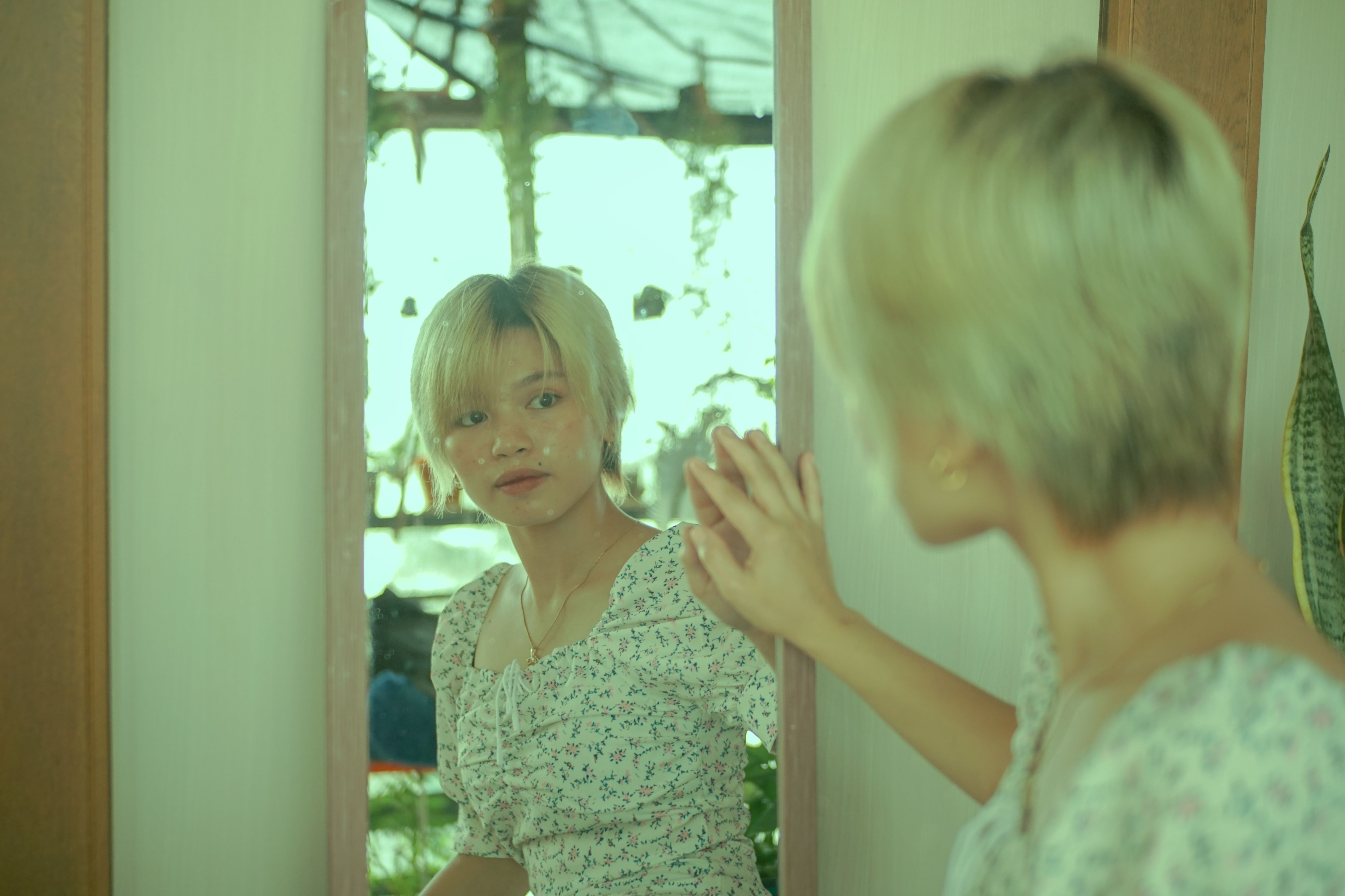 거울을 보며 자신의 두피 상태를 진지하게 확인하는 사람, 탈모 초기 증상 발견의 중요성을 강조