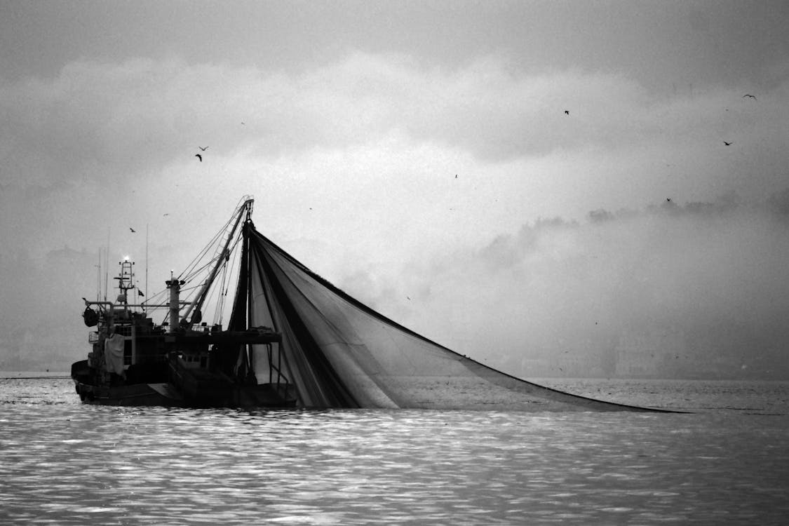 Grayscale Photo of Fishing Boat on Body of Water