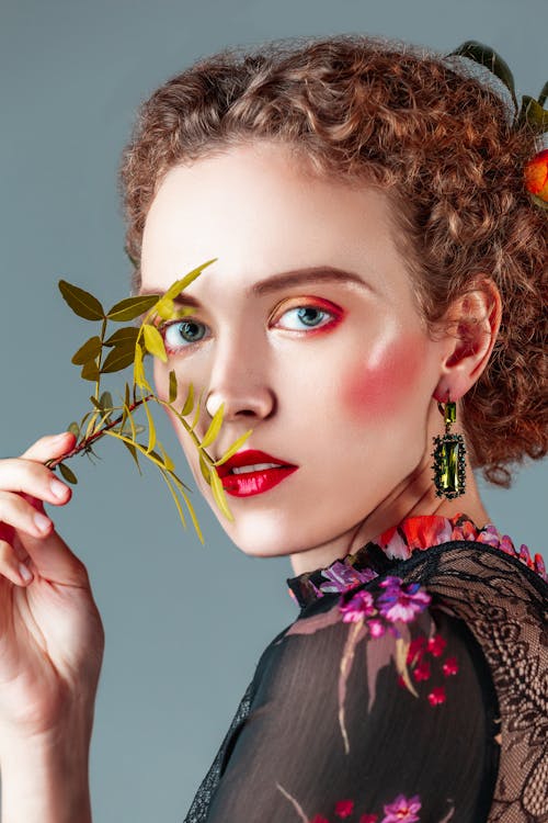 Beautiful Woman with Red Lipstick Holding Leaves