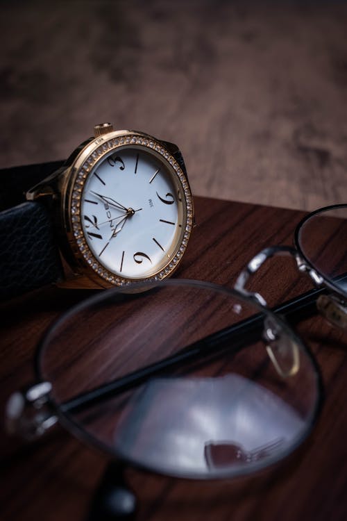 Eyeglasses and wristwatch on wooden surface