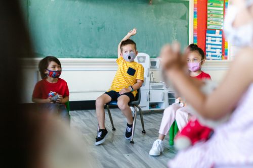 Free Preschool children wearing face masks participate in classroom activities, adapting to new normal routines. Stock Photo