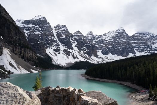 Stunning scenic view of Moraine Lake surrounded by snow-capped mountains and lush forest.