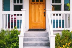 Inviting front porch of a suburban house featuring a wooden door and vibrant garden.