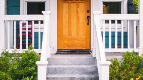 Inviting front porch of a suburban house featuring a wooden door and vibrant garden.