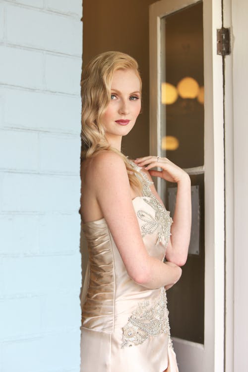 Woman in White Floral Lace Sleeveless Gown Leaning on the Wall