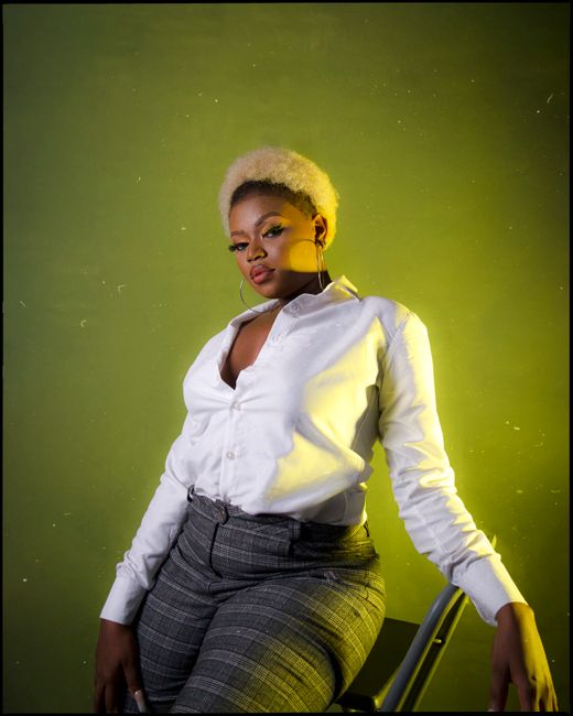 Portrait of a fashionable woman posing stylishly against a bright backdrop in a studio setting.