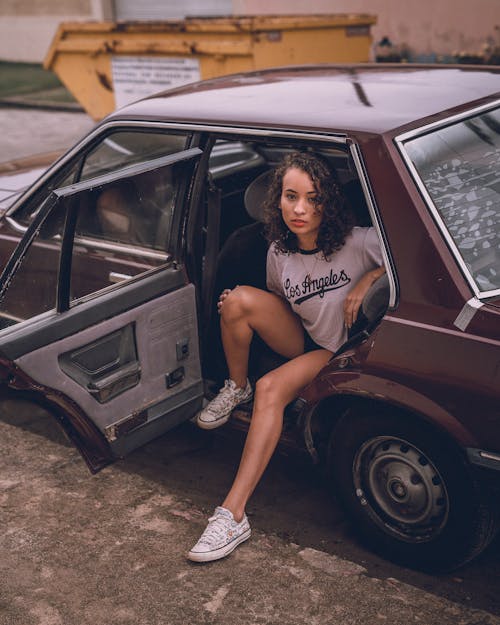 Young Woman Sitting Inside an Old Car while Looking at the Camera