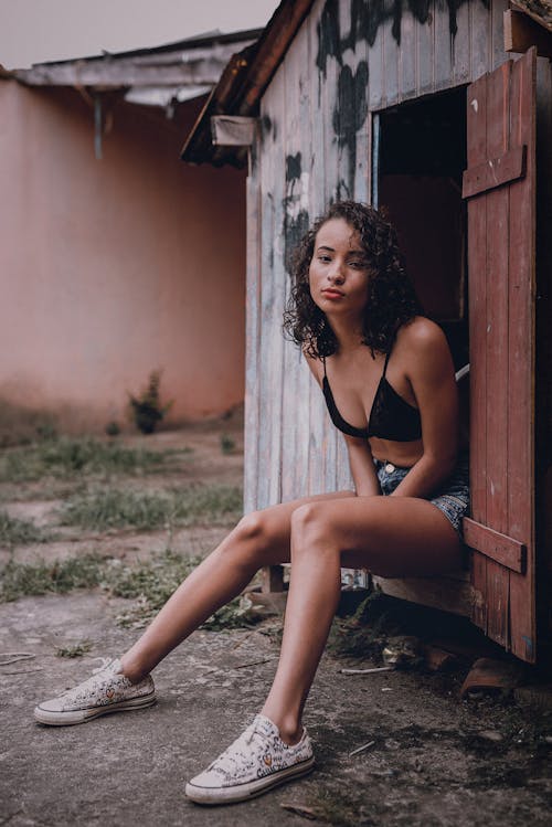 Woman in Black Bikini Sitting on a Wooden House