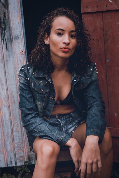 Woman in Blue Denim Jacket Sitting on Doorway