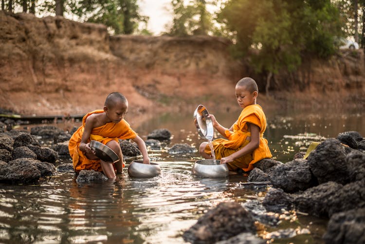 Young Monks Filling The Bowls With River Water