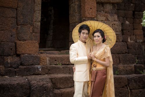 Free A couple in traditional Asian clothing poses with an umbrella at historic ruins, showcasing cultural heritage. Stock Photo