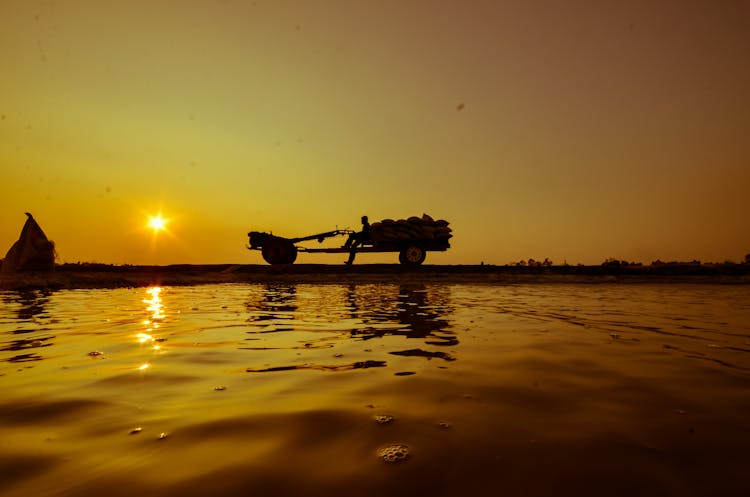 A Silhouette Of A Person On A Tractor With Stacked Sacks