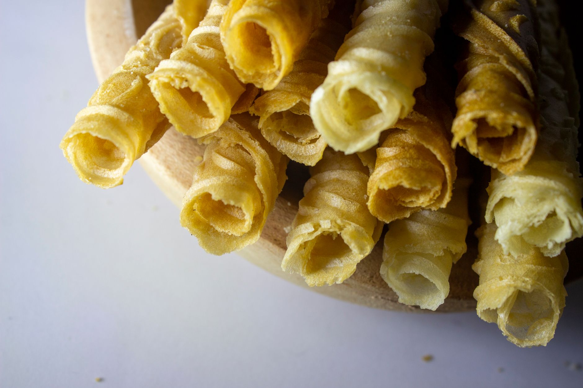 Tempting close-up shot of crispy barquillos in a wooden bowl.