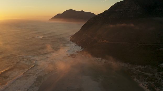 A stunning aerial view of coastal mountains and the ocean at sunset, capturing nature's beauty.