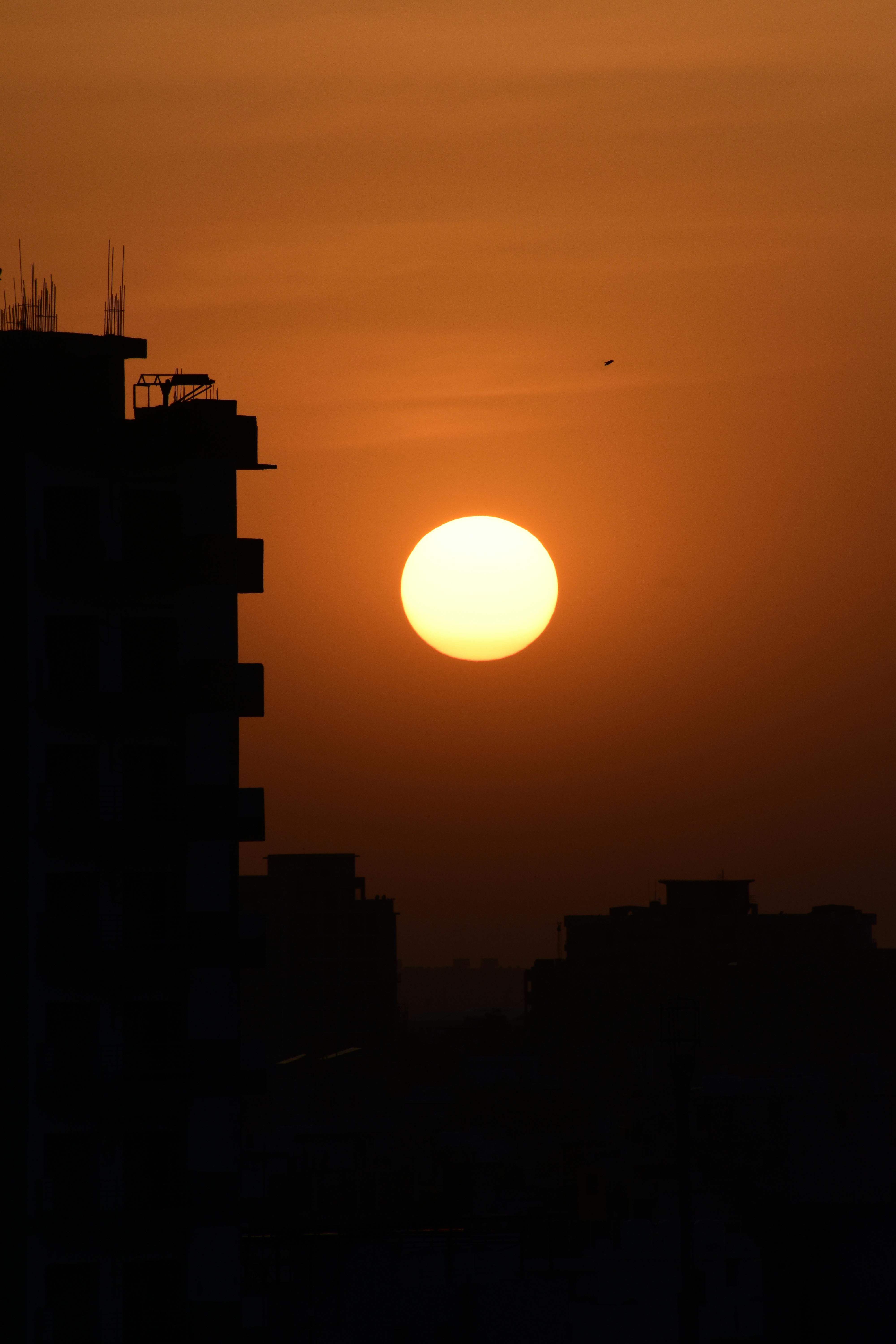 Silhouette of buildings against a vibrant sunset in Gurugram, India.