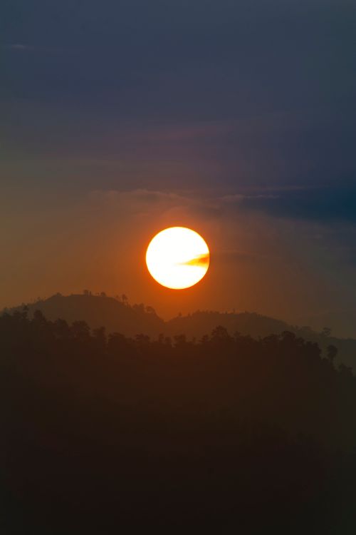 Free A stunning sunset over silhouetted hills with a clear, vibrant sky. Stock Photo
