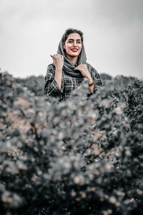 Free Portrait of a smiling Middle Eastern woman outdoors in nature, surrounded by greenery. Stock Photo