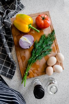Colorful farm produce on a wooden chopping board with eggs, perfect for fresh cooking inspiration.