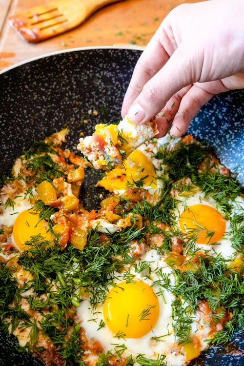 Free A Person Holding a Bread Near the Pan with Eggs Stock Photo