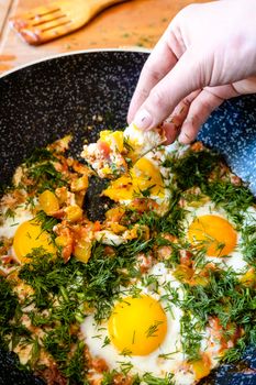 Close-up of shakshouka in a frying pan with eggs and fresh dill.