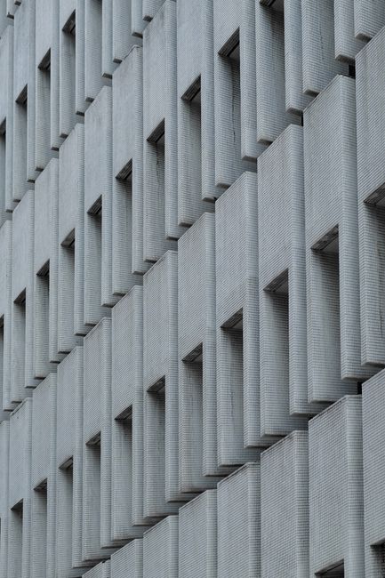 Close-up of a modern building exterior showcasing geometric concrete patterns and windows.