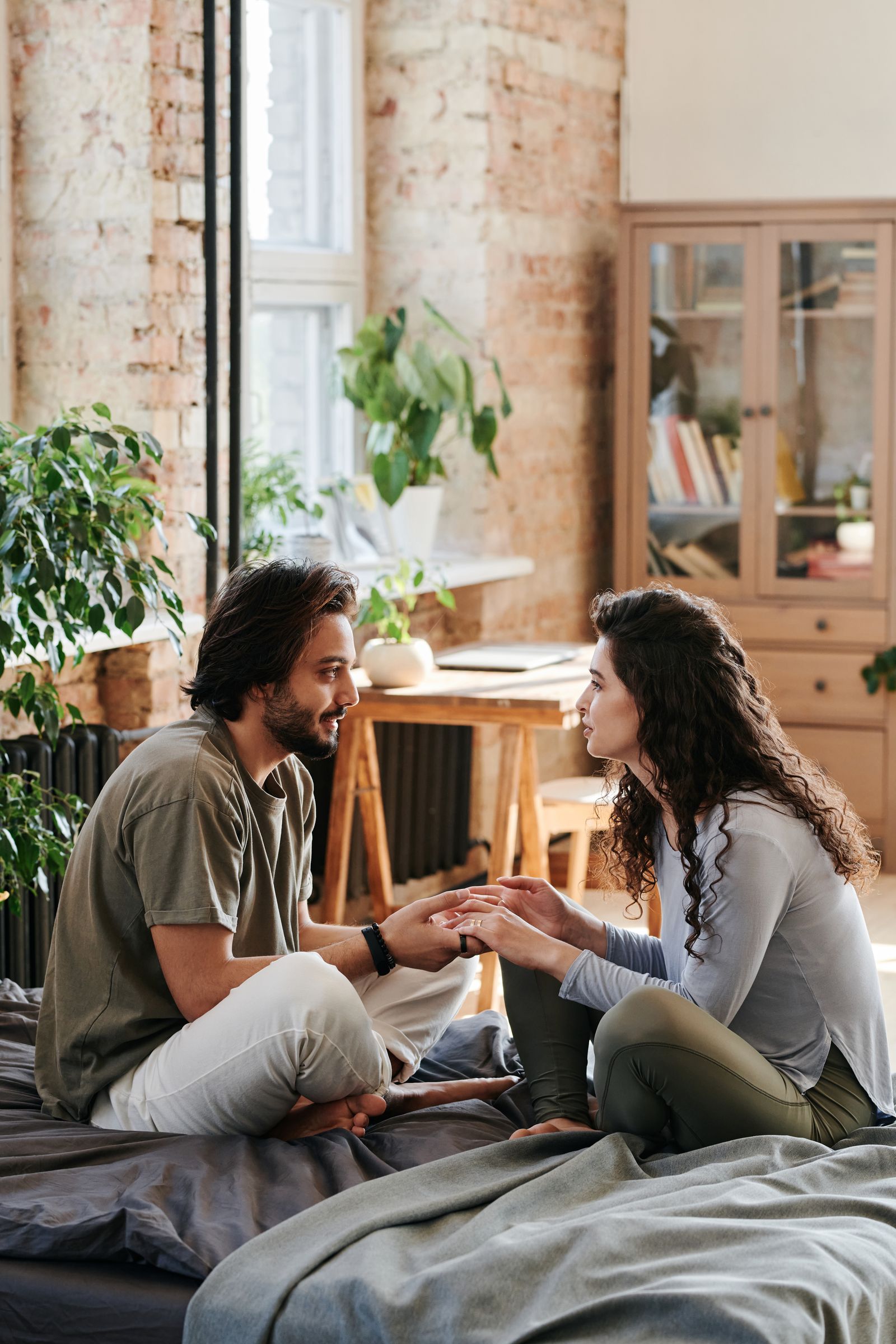 A couple holding hands and talking through an uncertain moment at home