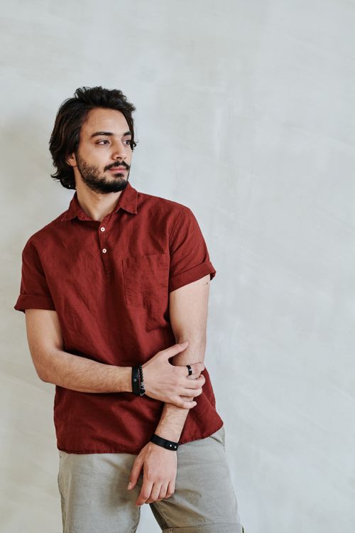 Free Confident young man with a beard in a red polo shirt posing against a white background. Stock Photo