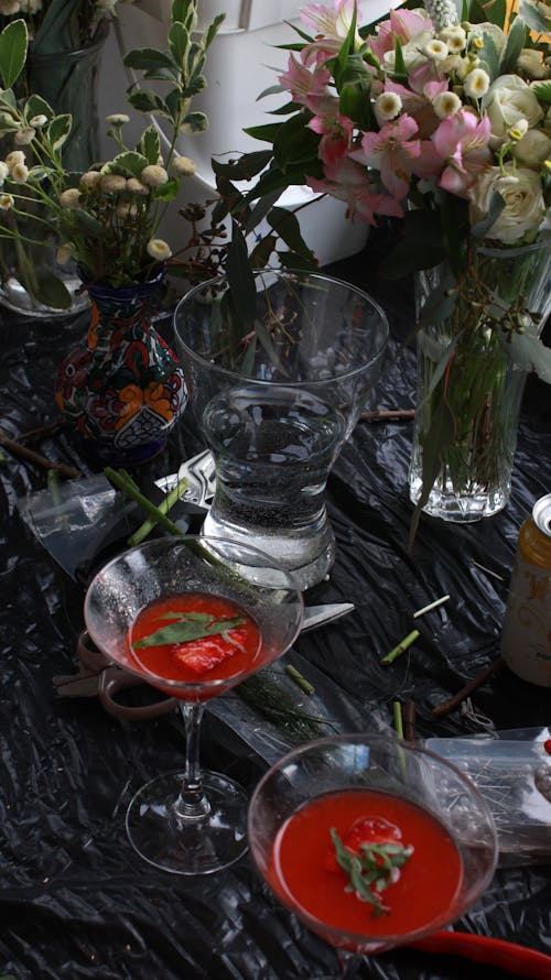 Glasses of Drinks Beside Vases with Flowers 