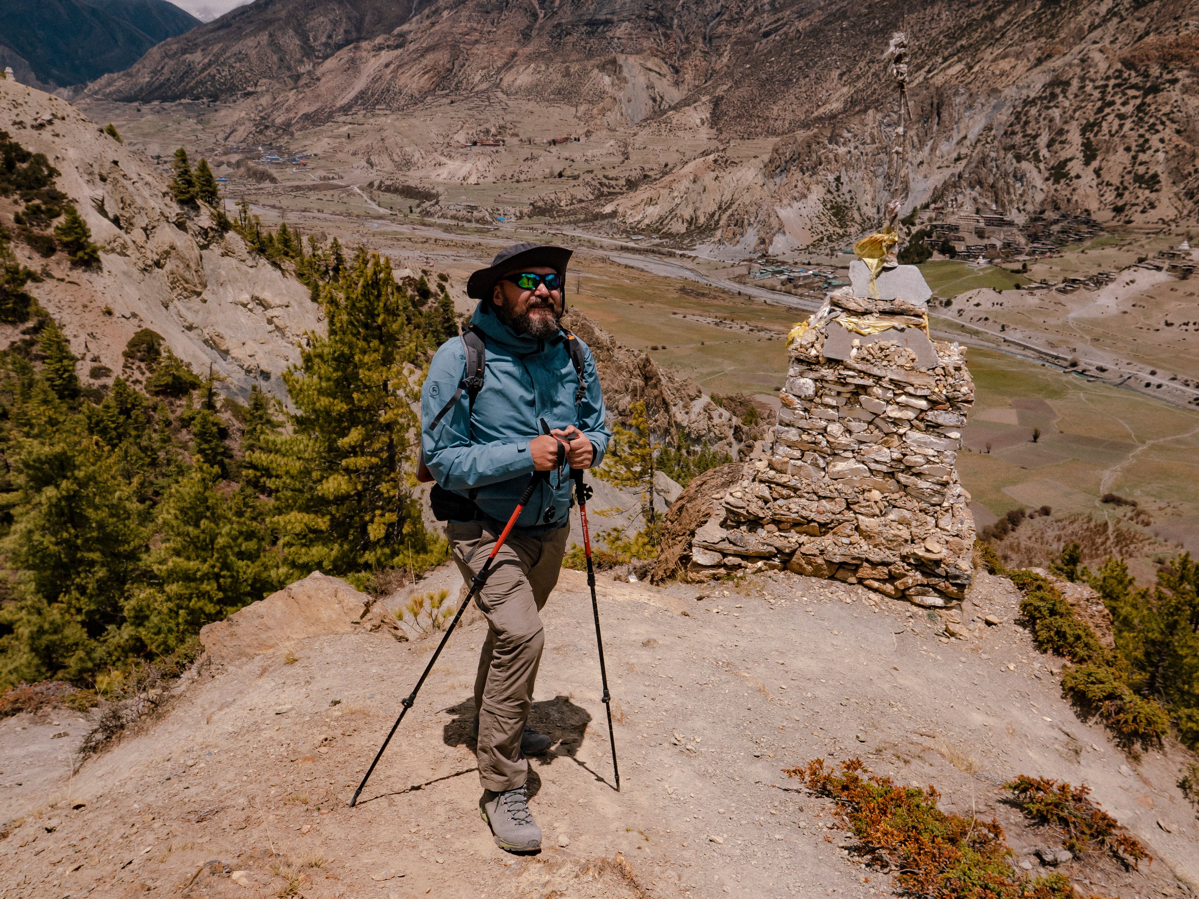 Hiker using trekking poles on a rugged mountain trail during a sunny day climb
