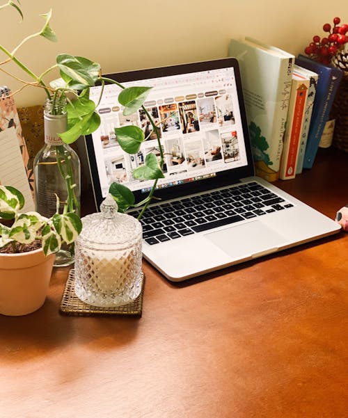 Free Laptop Beside a Potted Plant and Books on a Wooden Surface Stock Photo