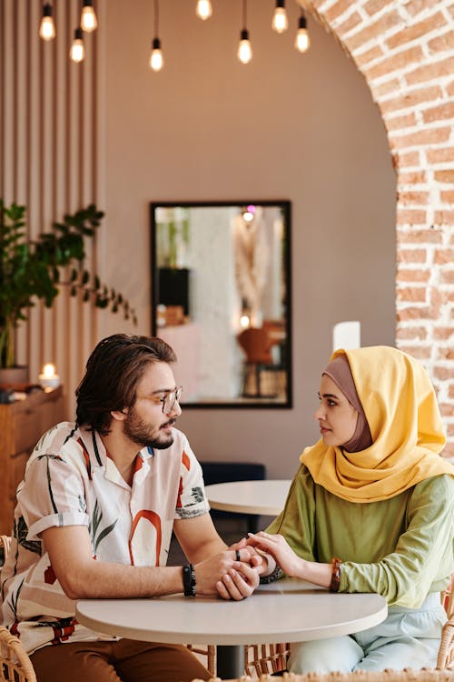 Free Bearded Man Holding the Hands of a Woman Wearing Hijab Stock Photo