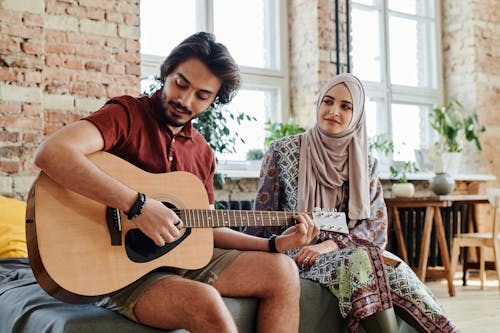 Man Playing Guitar Beside a Woman