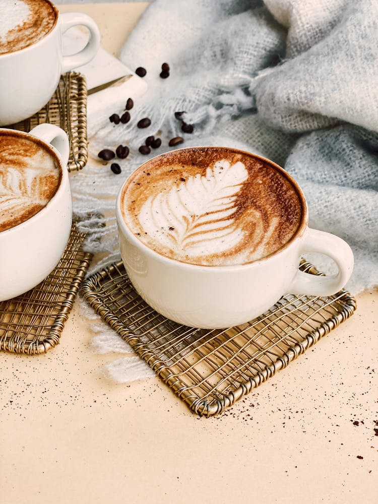 A Cup Of Coffee With Latte Art On Coasters