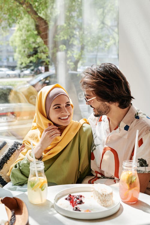 Free Woman in Yellow Hijab Sitting Beside Man in White Button Up Shirt Stock Photo